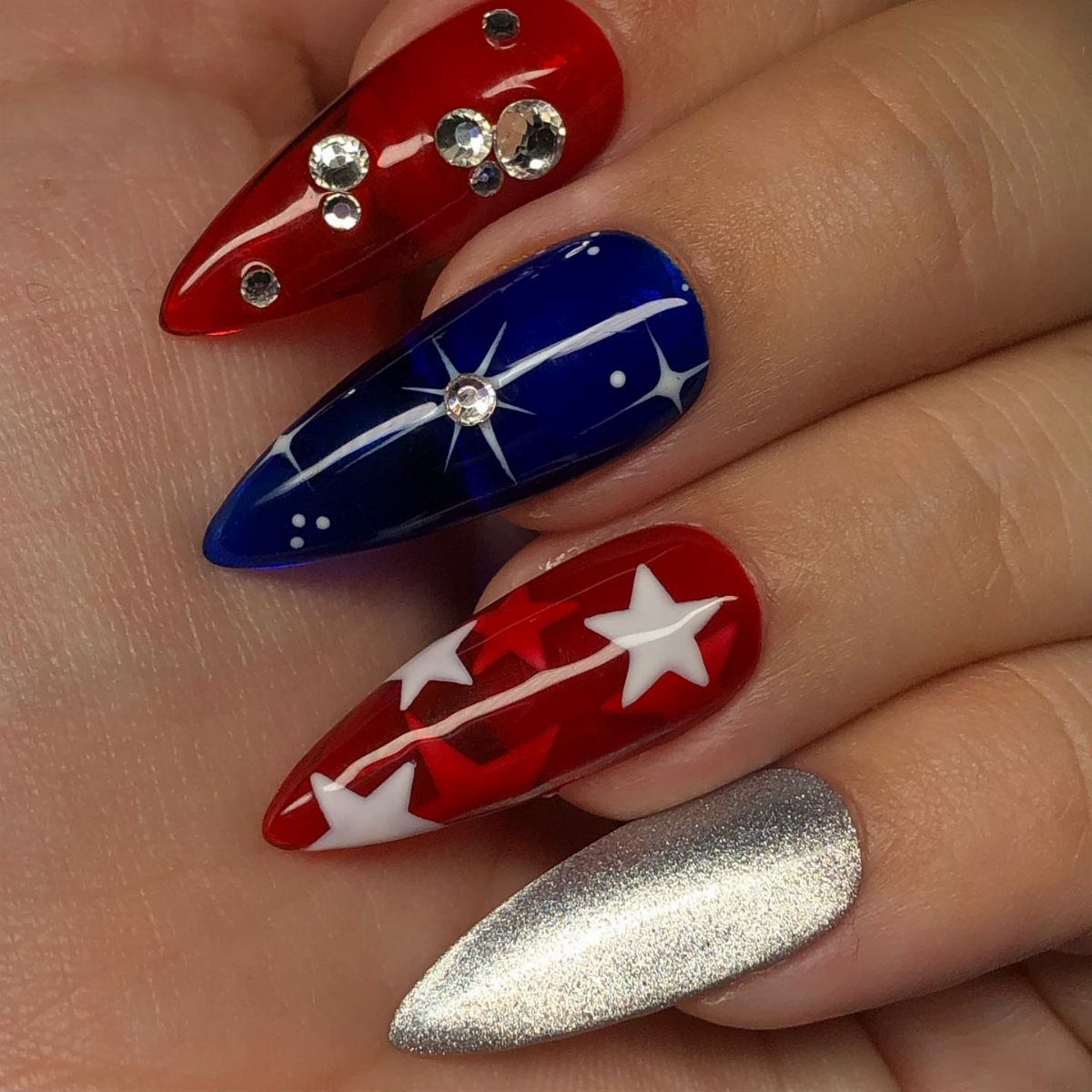 Patriotic red, white, and blue almond nails decorated with stars and sparkling rhinestones.