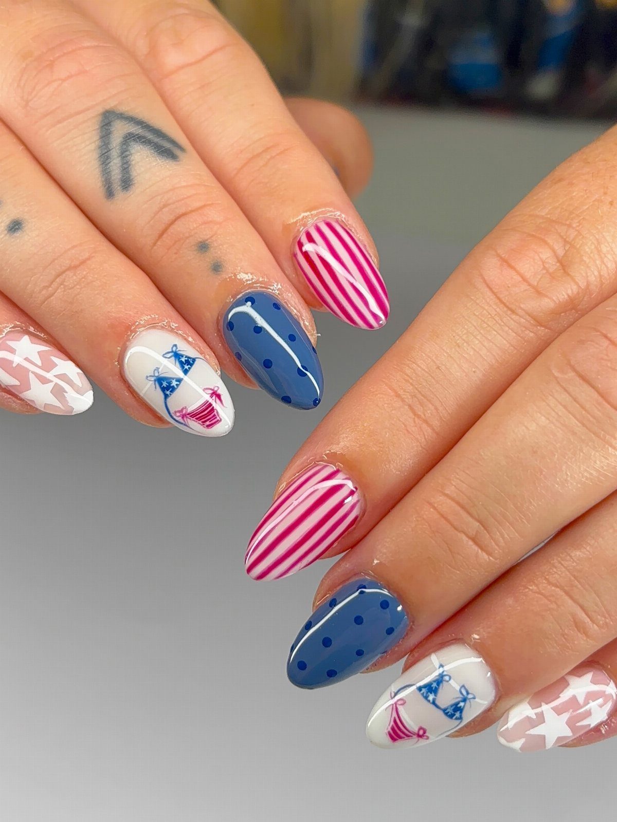 Almond-shaped nails with red stripes, blue polka dots, and beach chair art.