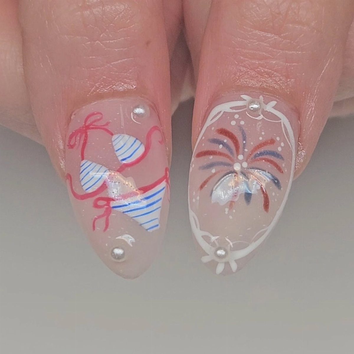 Nails featuring red, white, and blue bikini and firework art with small pearls.