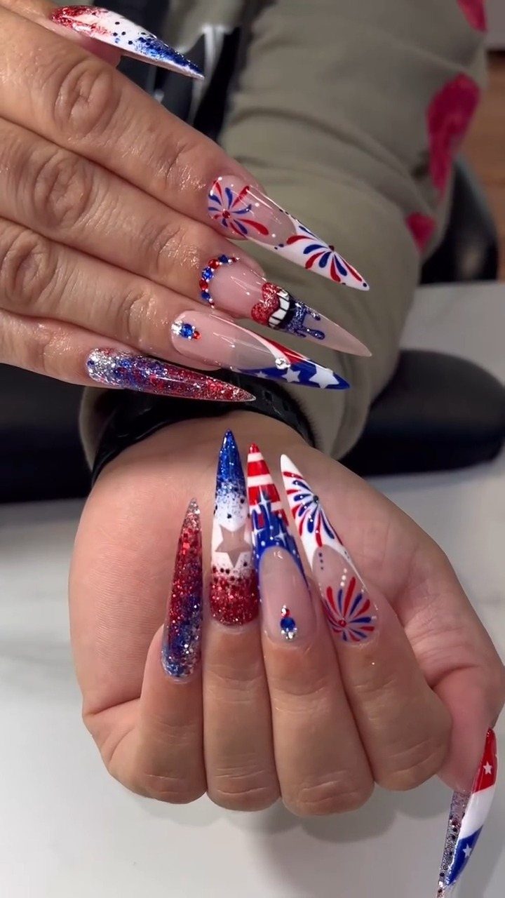 Long stiletto nails with red, white, and blue patriotic firework and star designs.