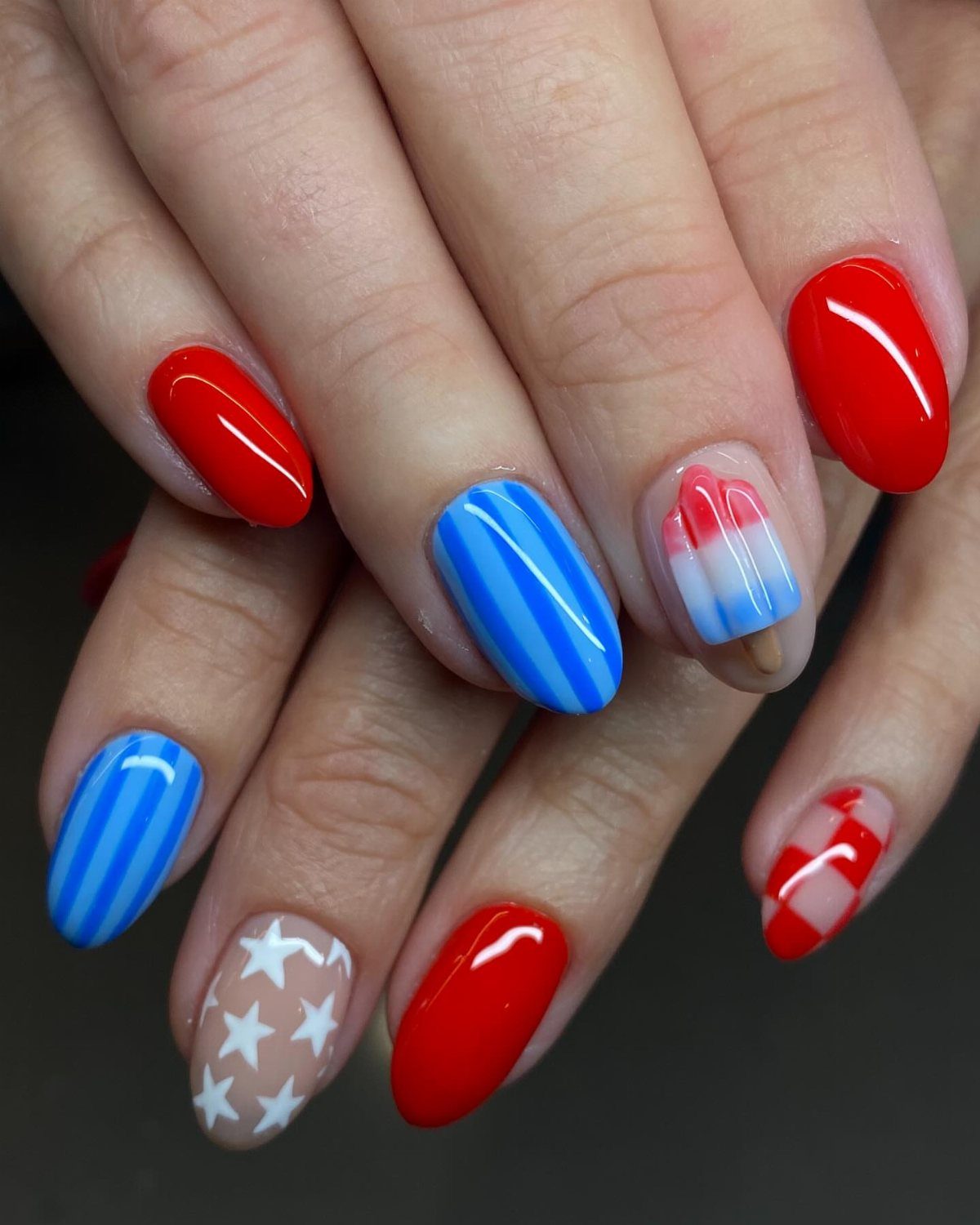 Almond-shaped nails with red, white, and blue patriotic patterns and ombre designs.