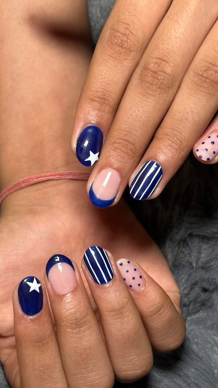 Blue and nude manicured nails featuring stars, polka dots, and stripes.