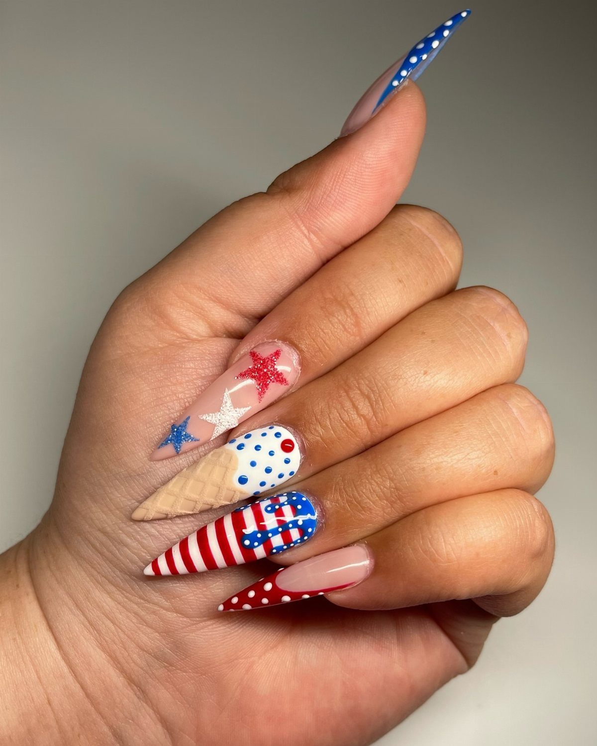 Patriotic red, white, and blue nail art with stars and ice cream cone design.