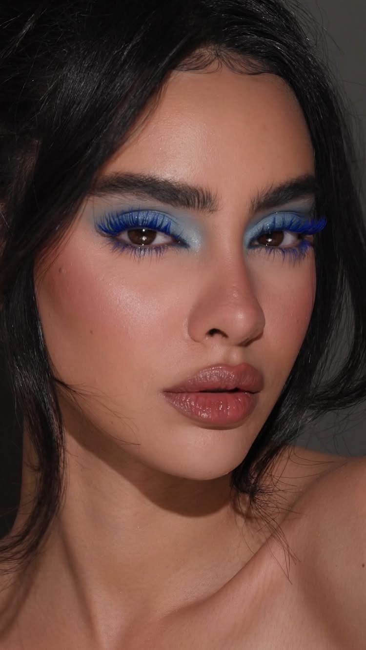 Woman with vibrant blue eyeshadow and neutral makeup looking at the camera.