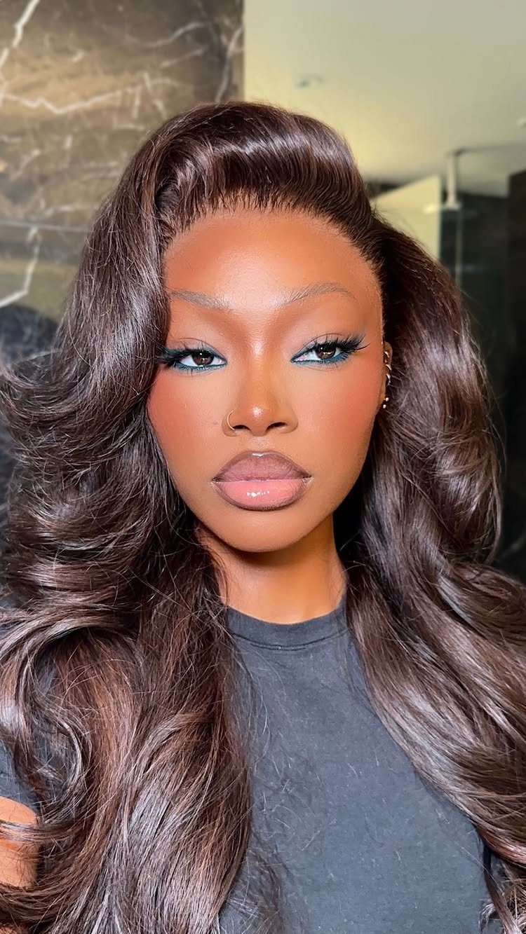 Woman with long brown hair wearing blue and bronze eyeshadow makeup.
