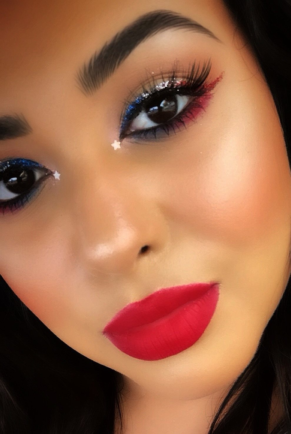 Woman with red, white, and blue eyeshadow, star decals, and red lipstick.