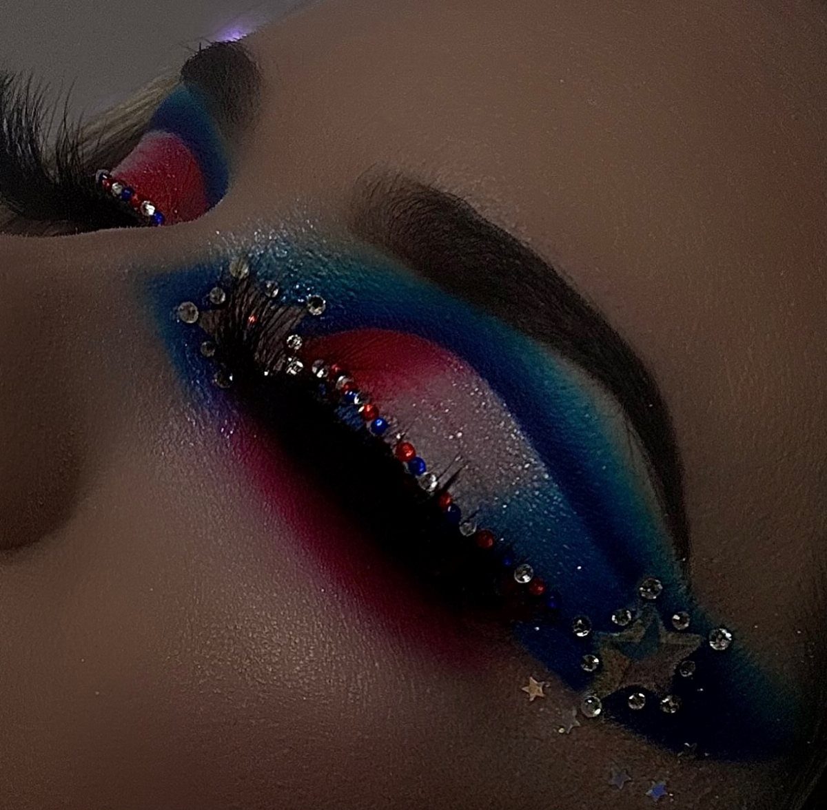 Eye makeup featuring red, white, and blue eyeshadow with rhinestones and star decals.