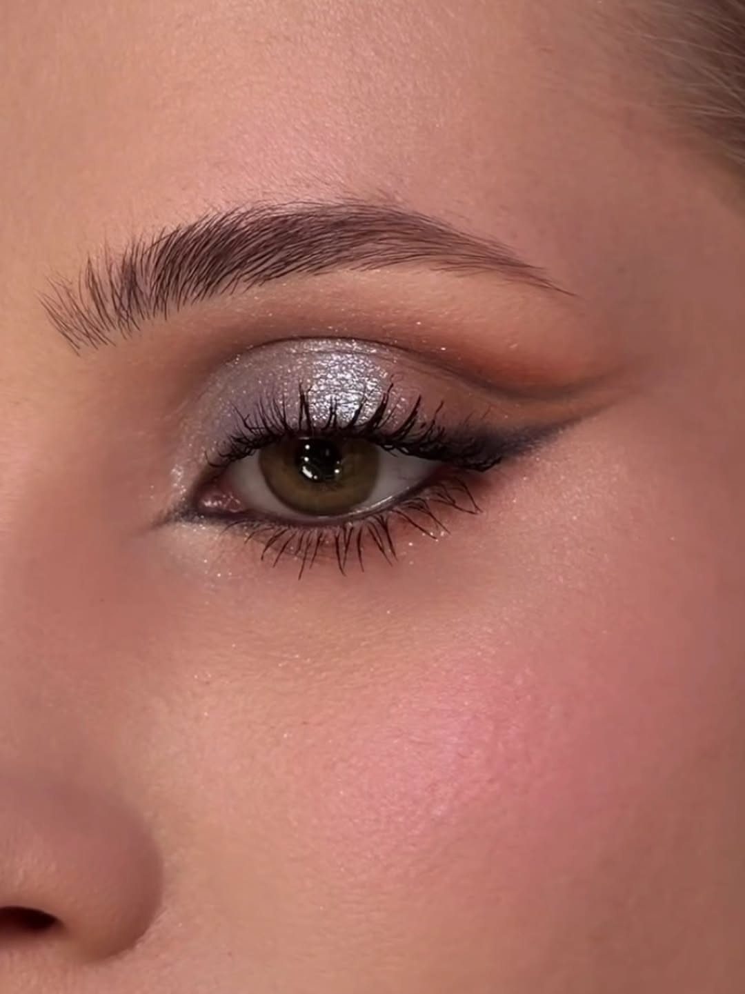 Eye with silver glitter eyeshadow and a sharp black winged eyeliner wing.