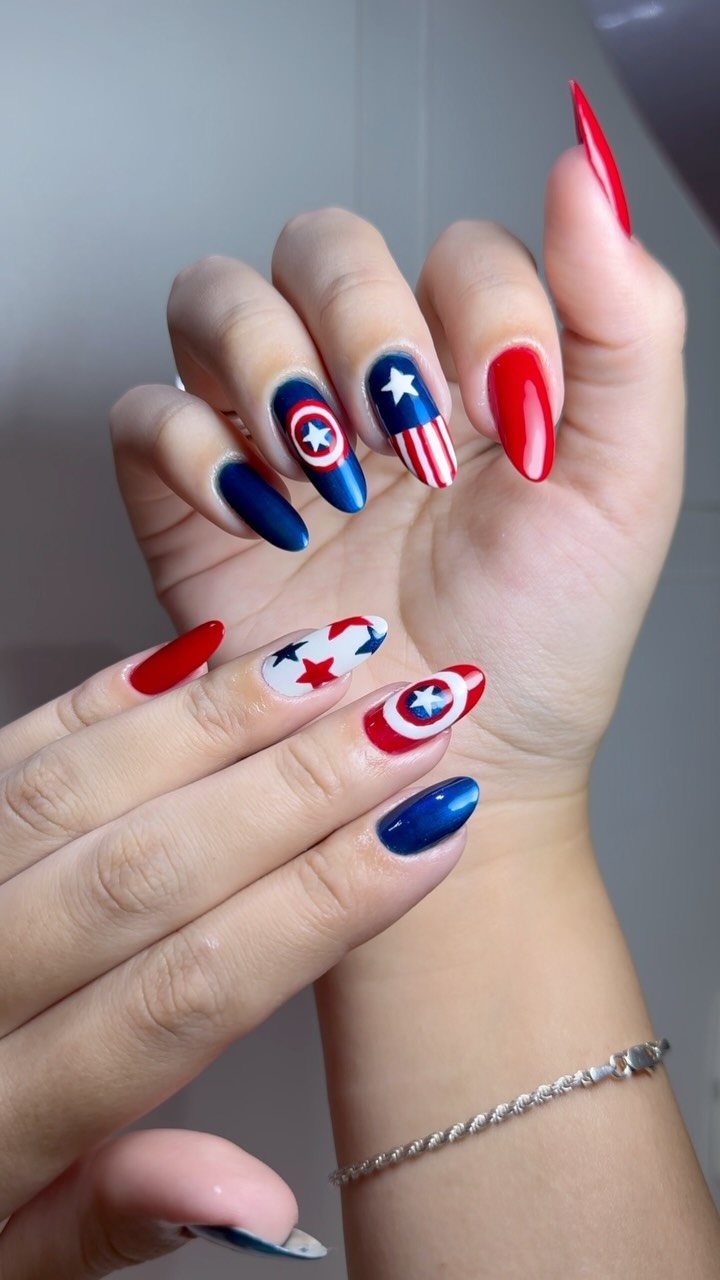 Almond-shaped gel nails with red, white, and blue patriotic stars and stripes designs.