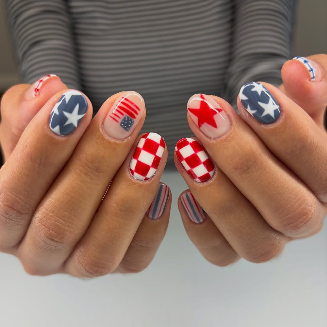 Patriotic nail art featuring red, white, and blue stars, stripes, and checkered patterns.
