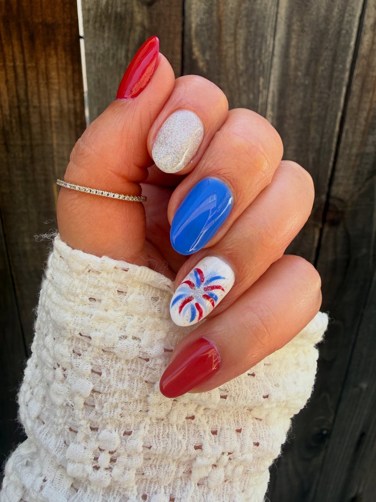 Almond-shaped gel nails in red, white, and blue with a detailed starburst design.