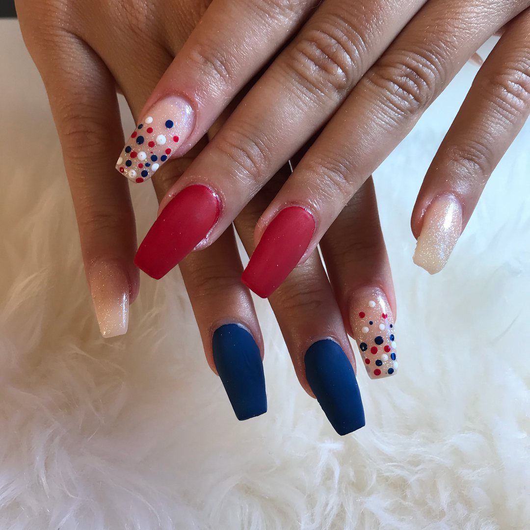 Long coffin nails with matte red, matte blue, and polka dot designs.