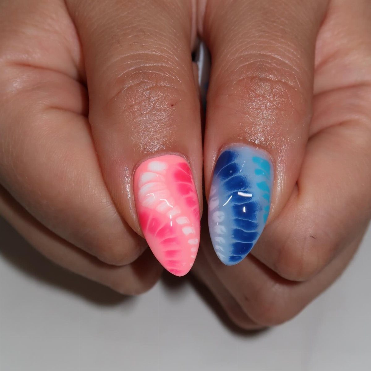 Two fingernails with red, white, and blue marbled gel nail art.