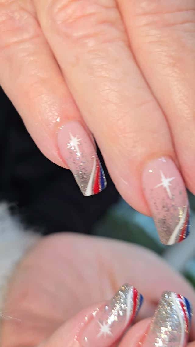 Nude gel nails with white stars and red, white, and blue tips.