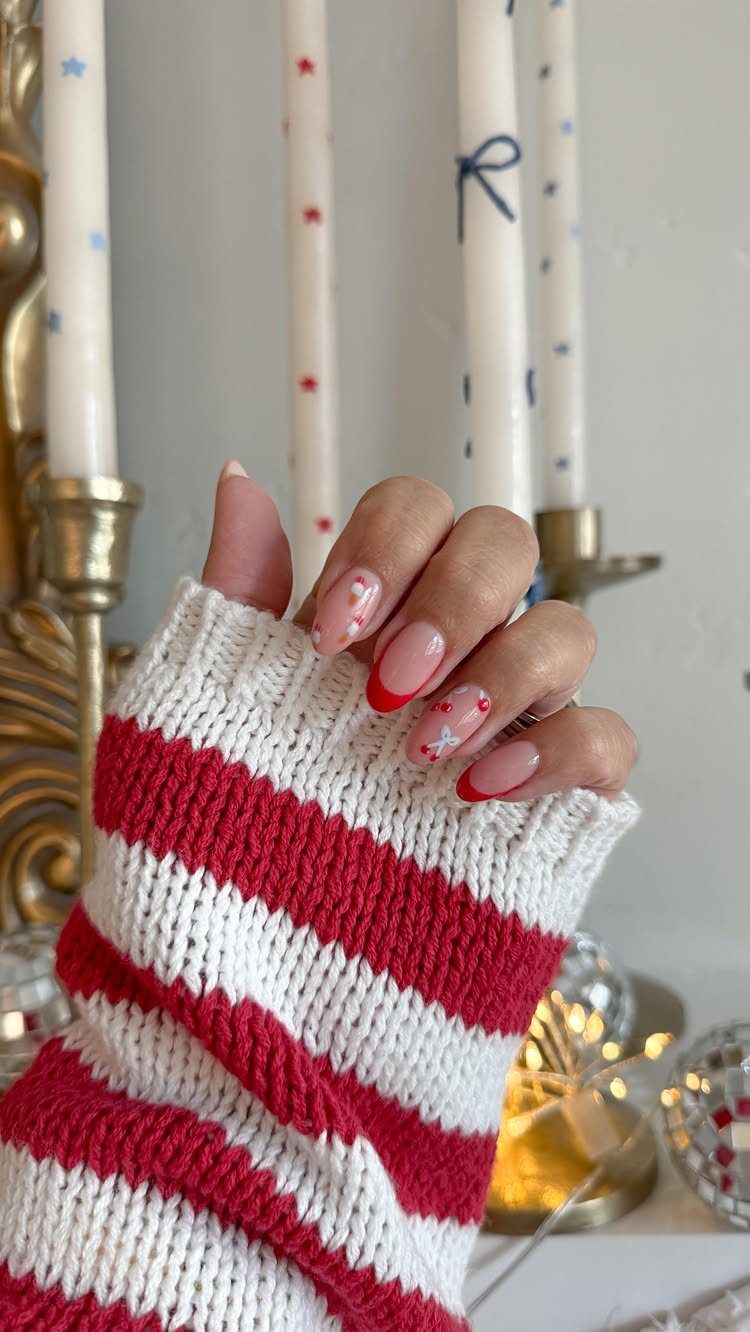 Red and white gel nails with star patterns and a striped sweater