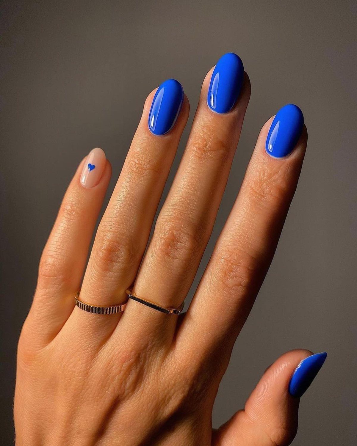 Hand with royal blue and nude gel nails featuring a small blue heart.