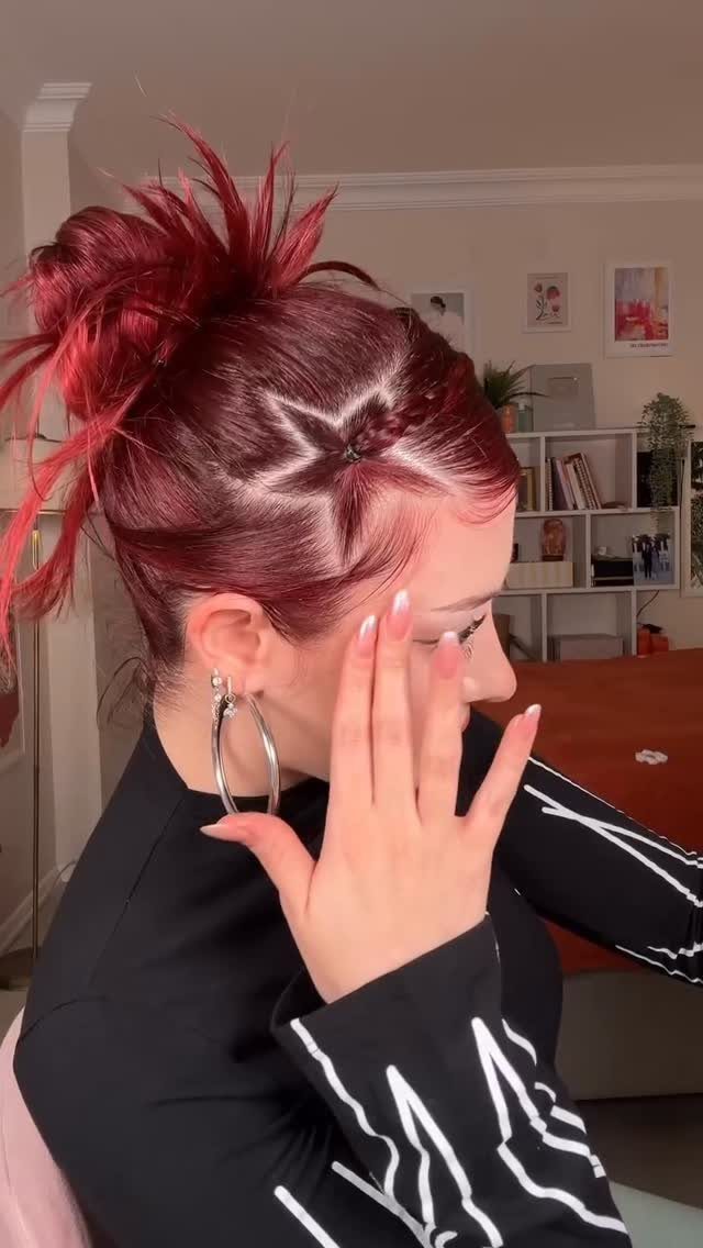 Woman with red hair featuring a star-shaped braid and a spiky high bun.
