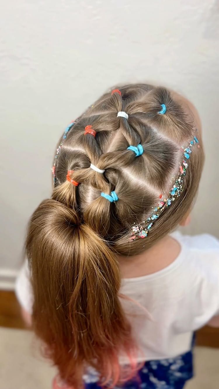 Girl's ponytail styled with red, white, and blue elastic bands and glittery hair.