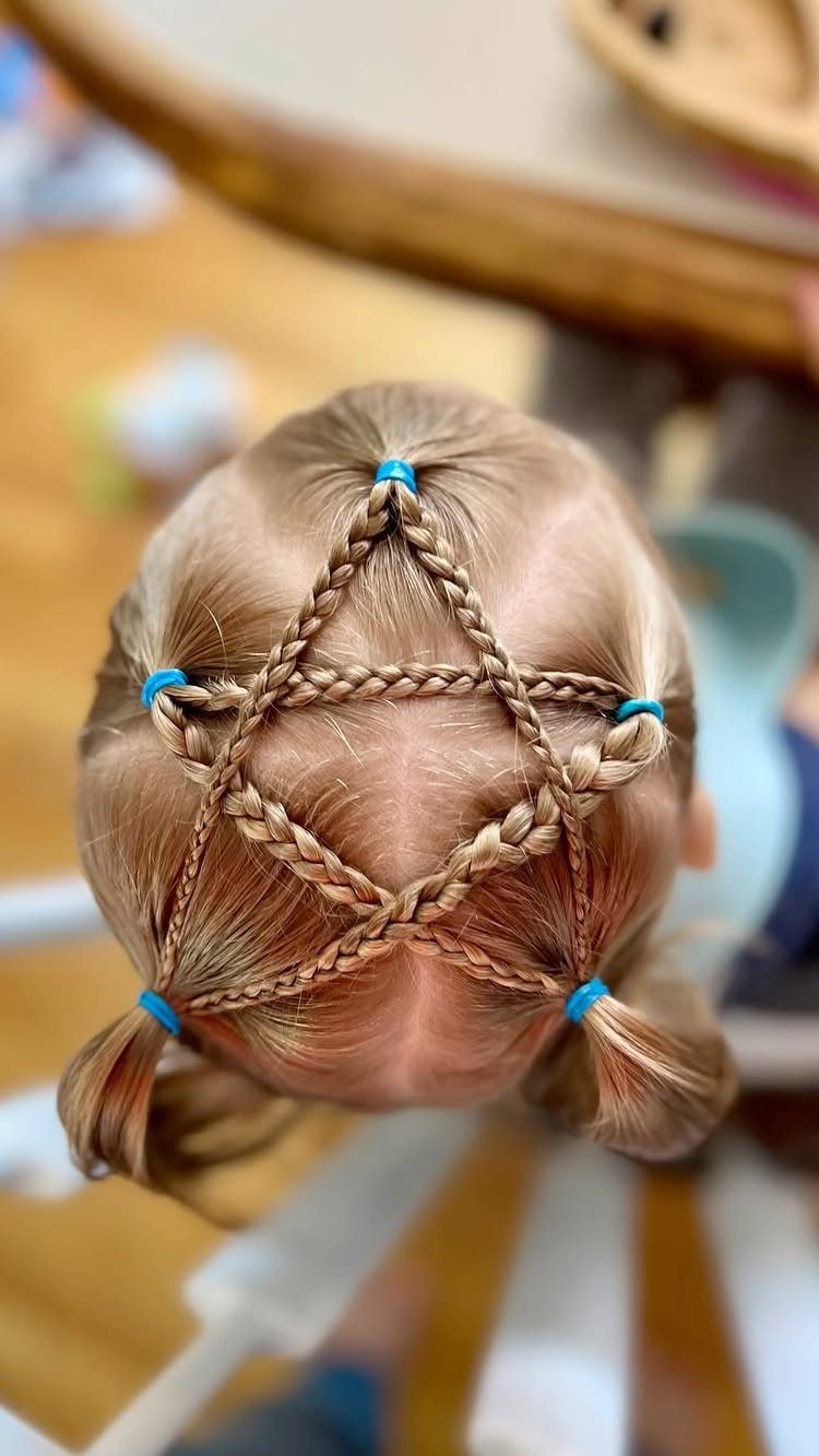 Child's light brown hair braided into a star shape with blue elastic bands.
