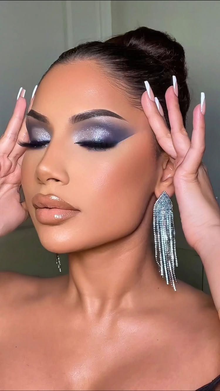 Woman with shimmering blue smokey eye makeup and long silver dangling earrings.