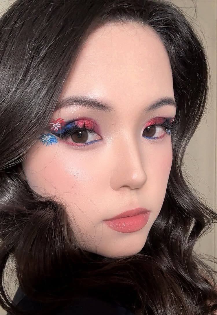 Woman with red and blue eyeshadow and star-shaped glittery eye makeup designs.