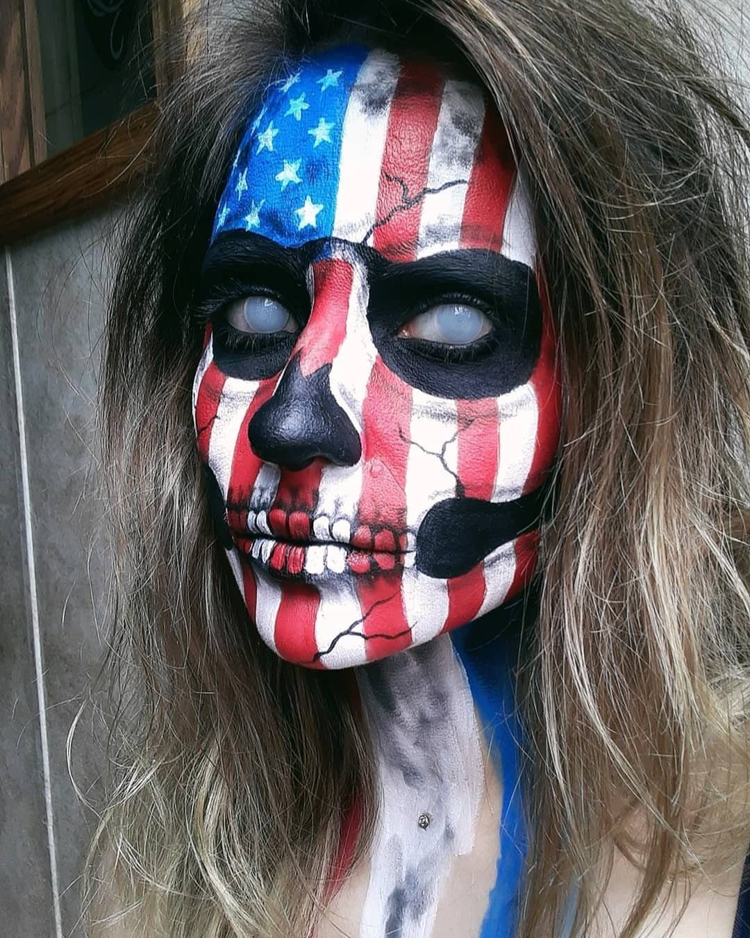 Person with skull face paint in American flag red, white, and blue colors.