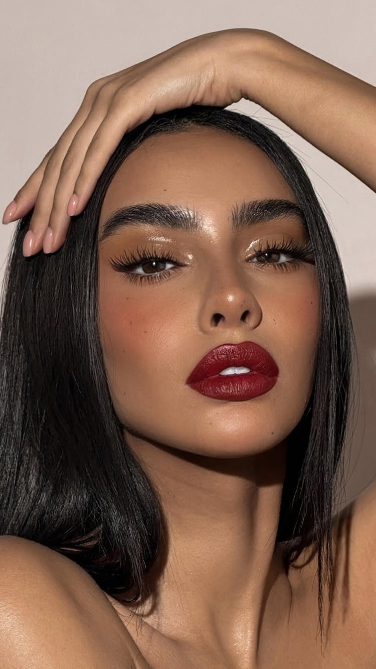 Woman with bold red lipstick and soft neutral shimmering eye makeup.