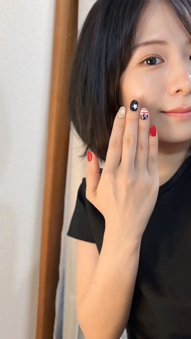 Woman's hand showing American flag nail art with red, white, and blue designs.