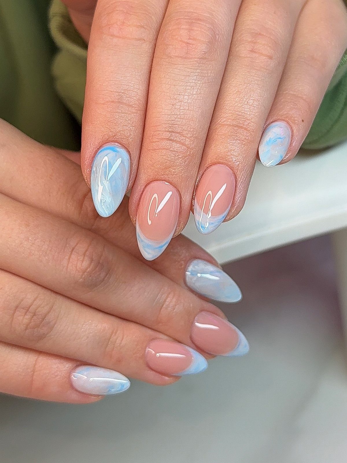 Almond-shaped nails with light blue and white marble swirls and French tips.
