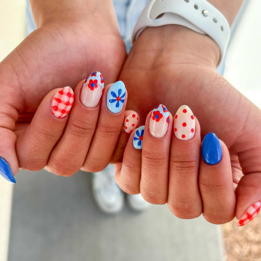 Almond-shaped nails with red, white, and blue patriotic patterns and floral designs.