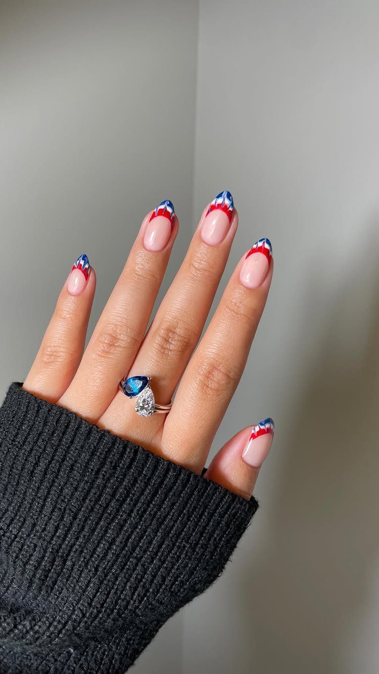 Hand with red, white, and blue French tip nails and a diamond ring.