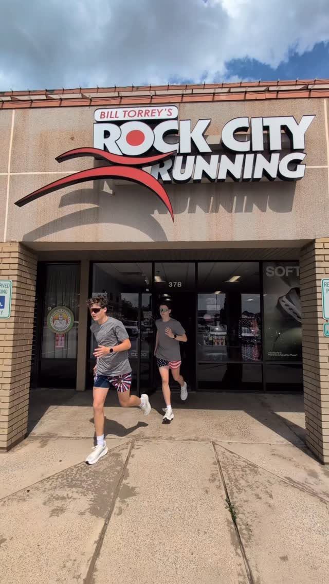 Two men running in patriotic red, white, and blue outfits outside a running store.