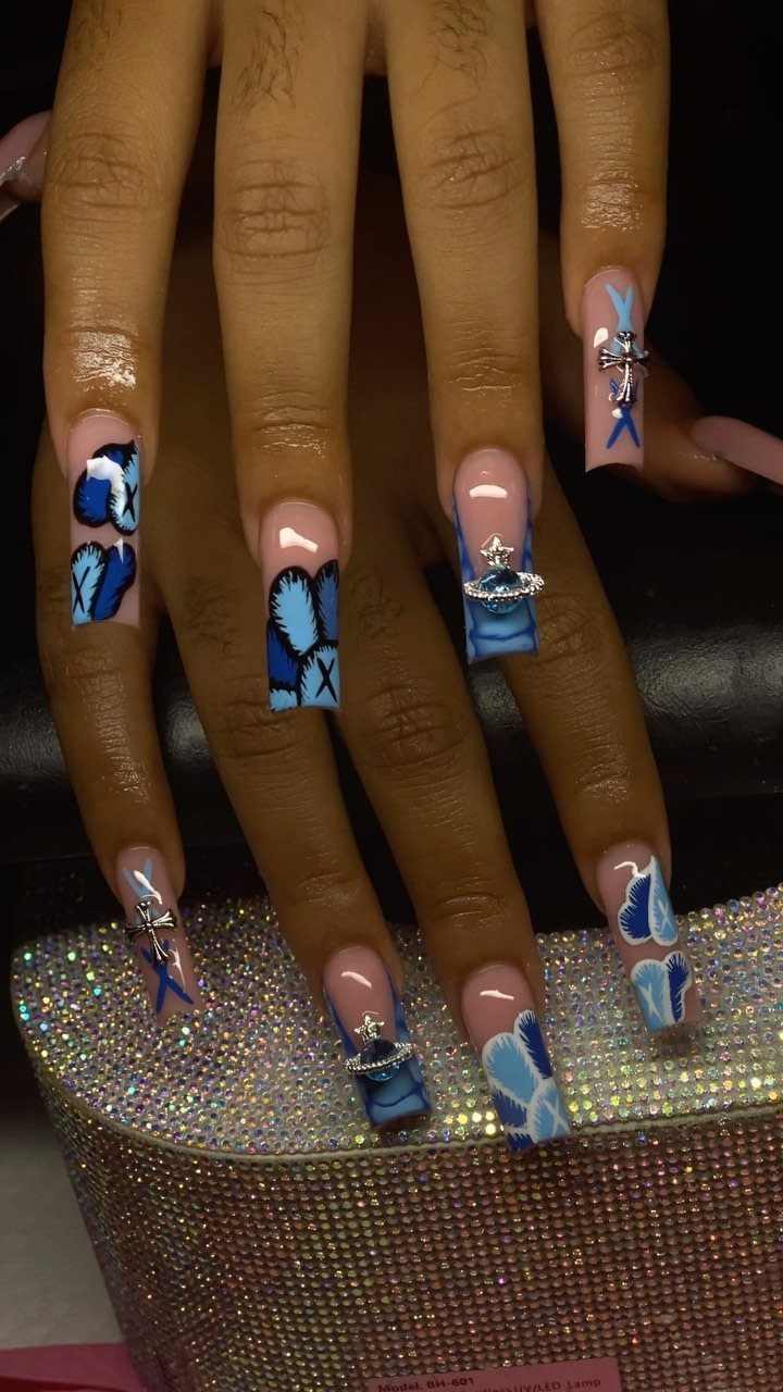 Long square acrylic nails with blue and white abstract art and silver charms.