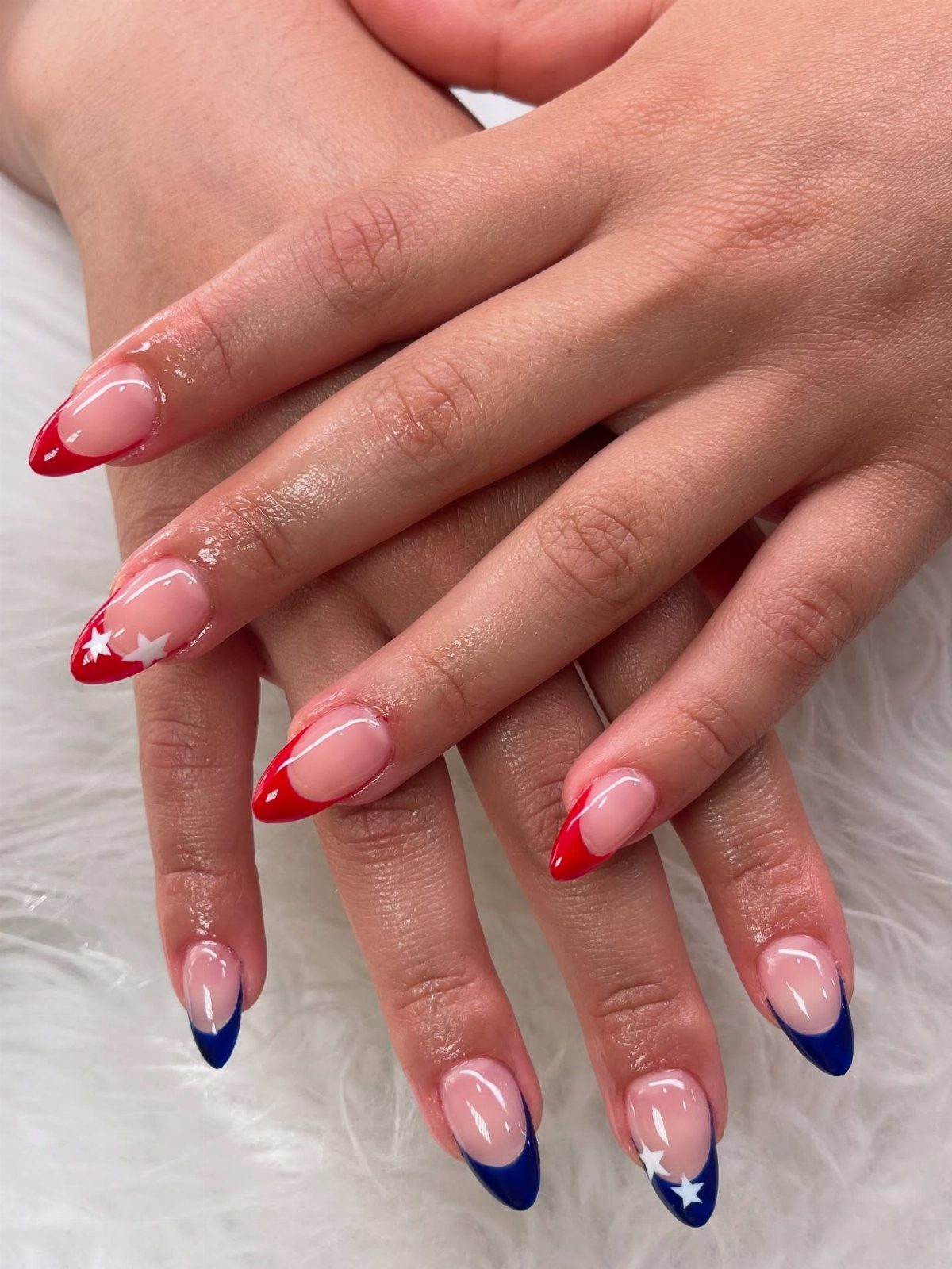 Acrylic nails with red, white, and blue French tips and stars on white fur.