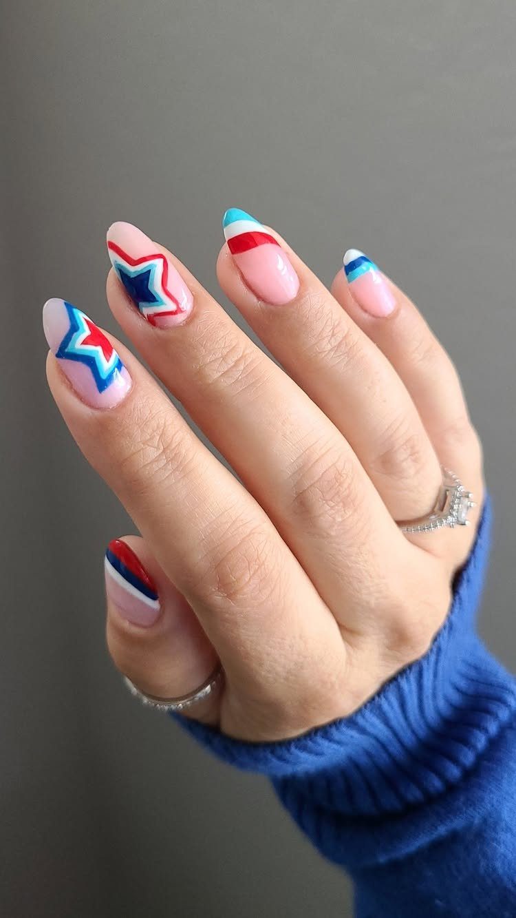 Acrylic nails with red, white, and blue stars and stripes on nude base.