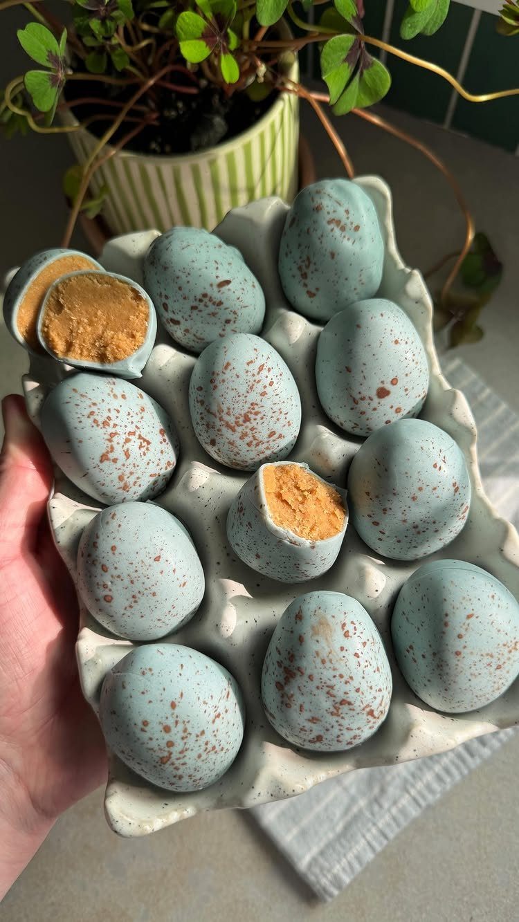 Blue speckled chocolate eggs in a white ceramic carton with brown filling