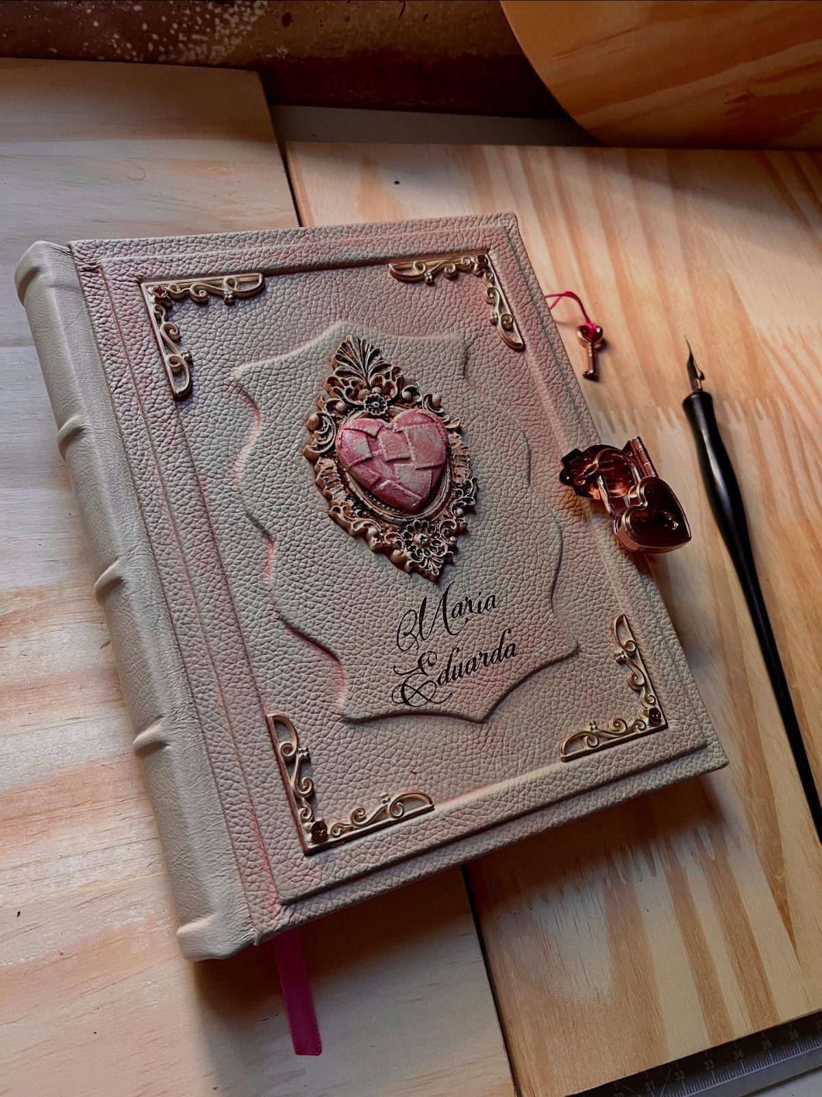 Ornate beige journal with a heart jewel and fountain pen on wooden table