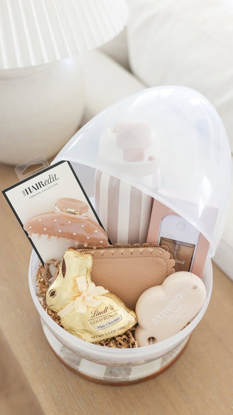 Egg-shaped clear container filled with chocolates, beauty products, and accessories for Easter.