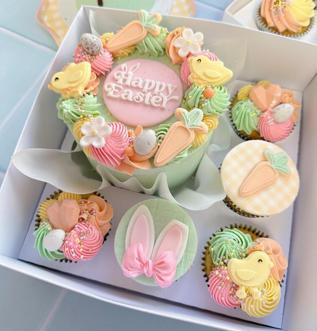 Pastel Easter cake and cupcakes with chicks and carrots in a white box