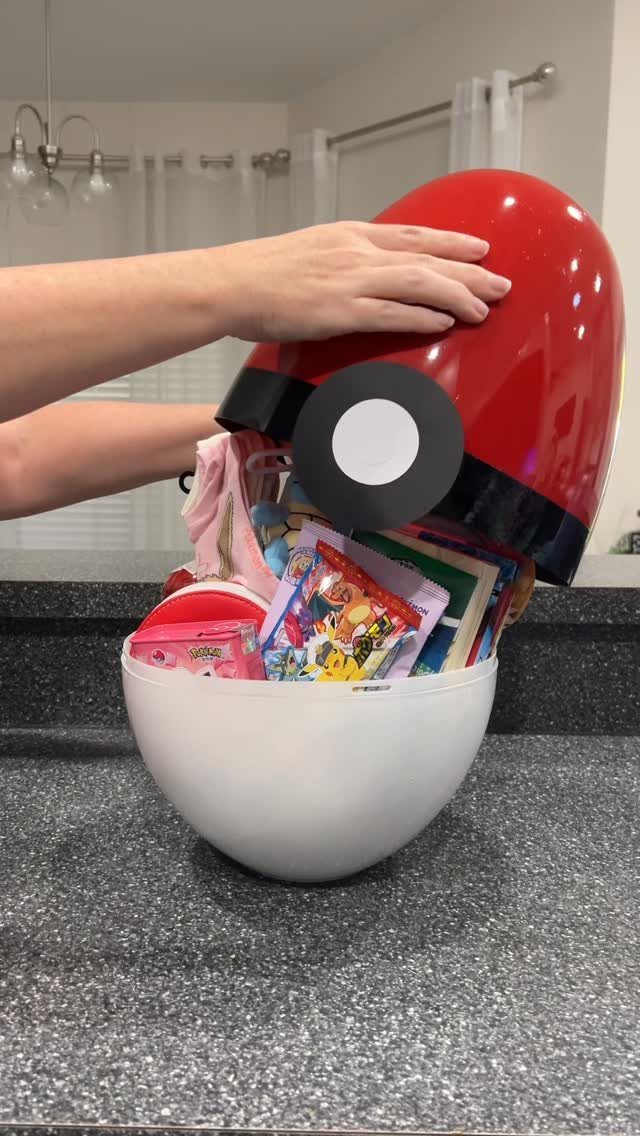 Pokéball shaped gift basket filled with colorful candies on a grey countertop