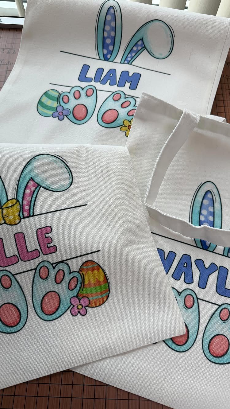 White fabric tote bags with colorful bunny and Easter prints and personalized names.