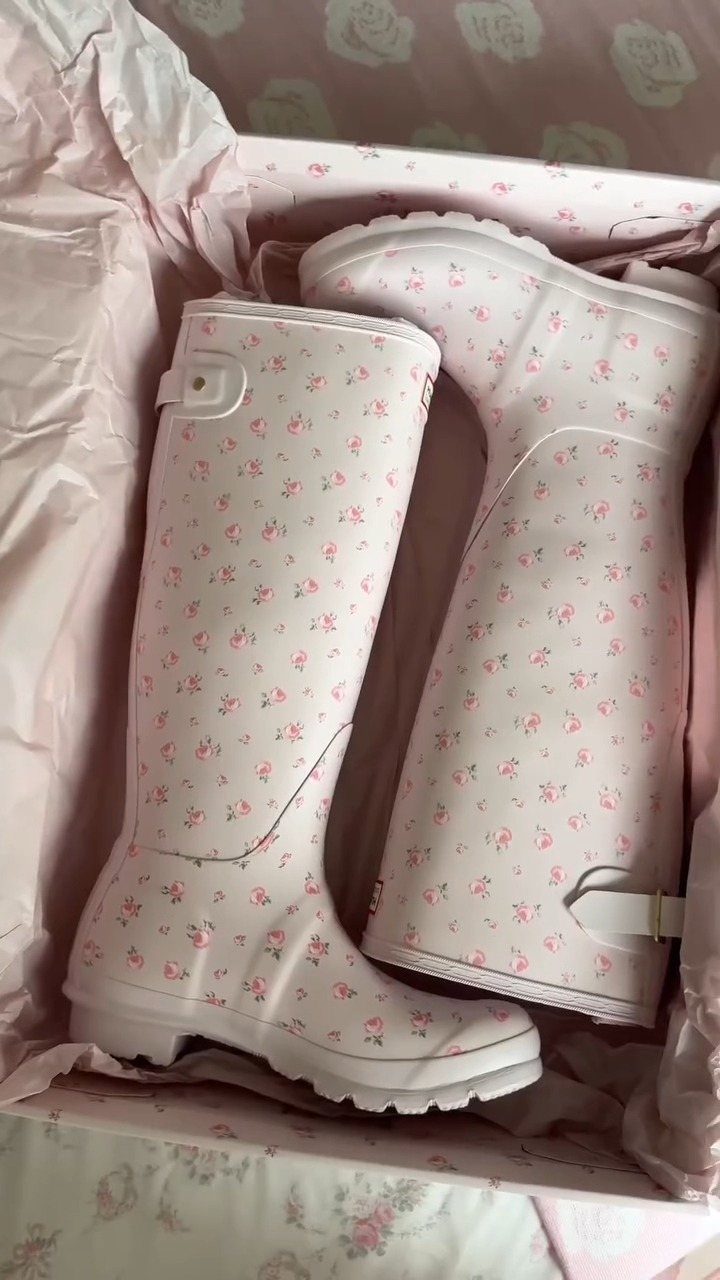 Pink floral rain boots inside a white gift box with pink tissue paper.