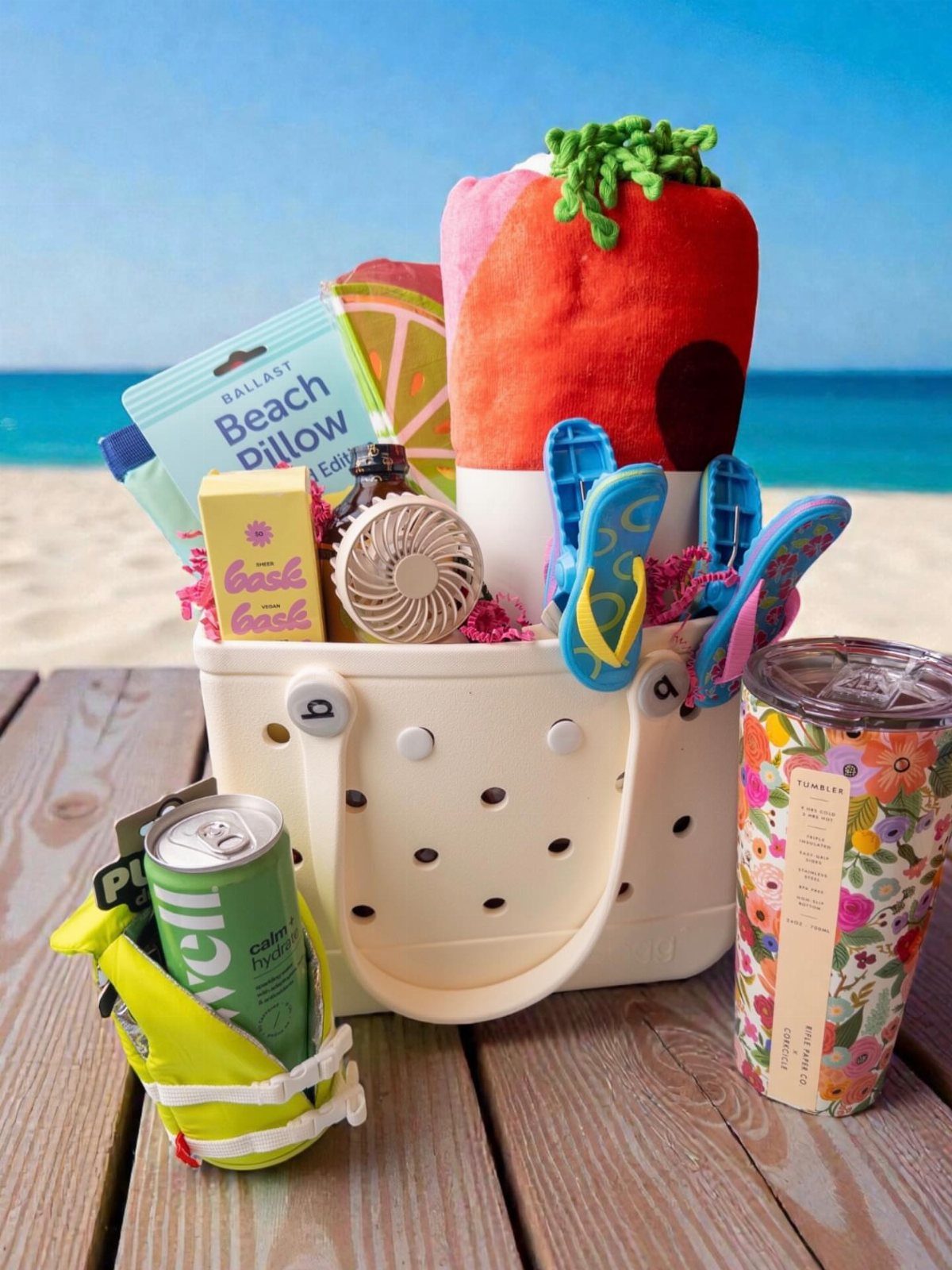 White plastic beach bucket filled with a red towel and swim gear on deck.