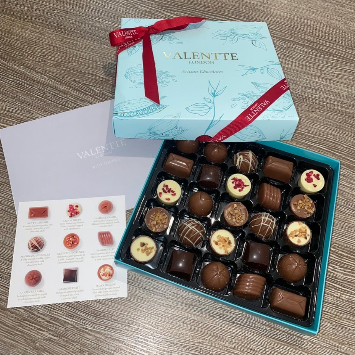 Assorted gourmet chocolates in a light blue box with a red ribbon.