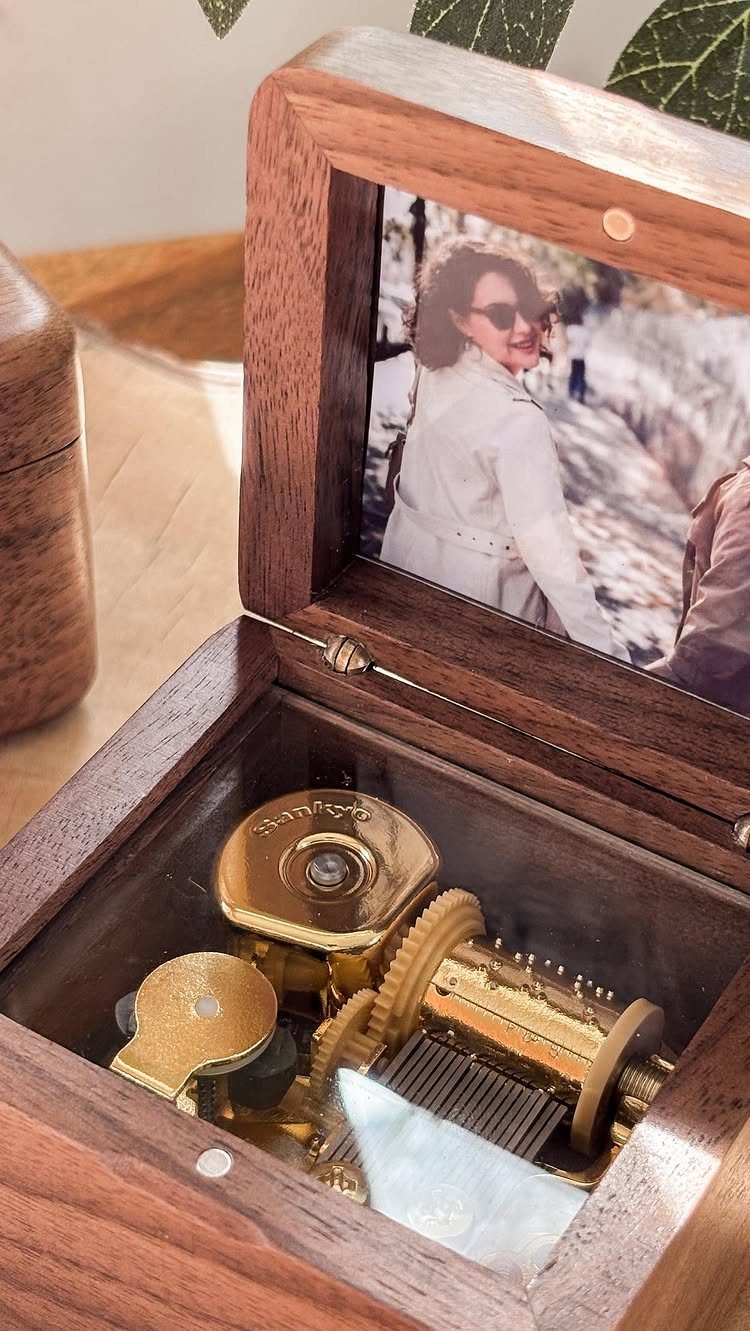 Wooden music box with gold gears and a photo of a woman inside.