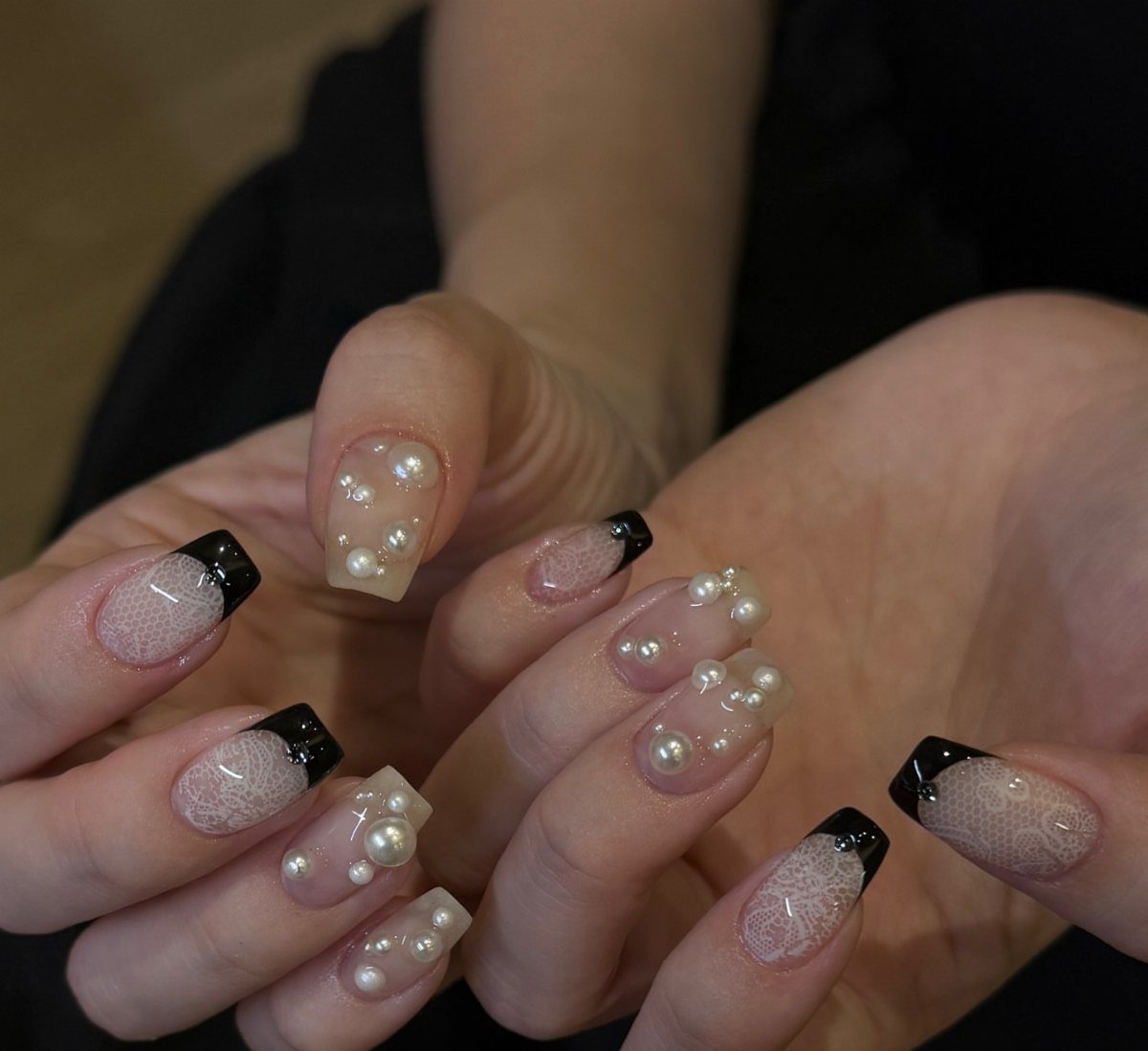 Almond nails with black French tips and 3D white pearl accents