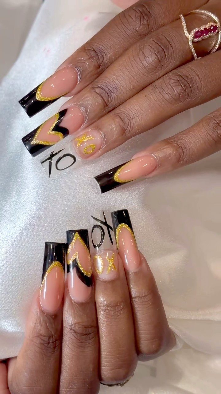 Long coffin nails with black French tips, gold glitter, and black heart accents.