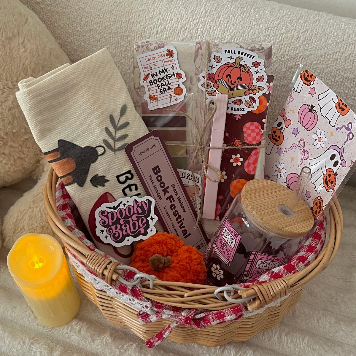 Wicker gift basket with autumn stickers, a small pumpkin, and a book bookmark.