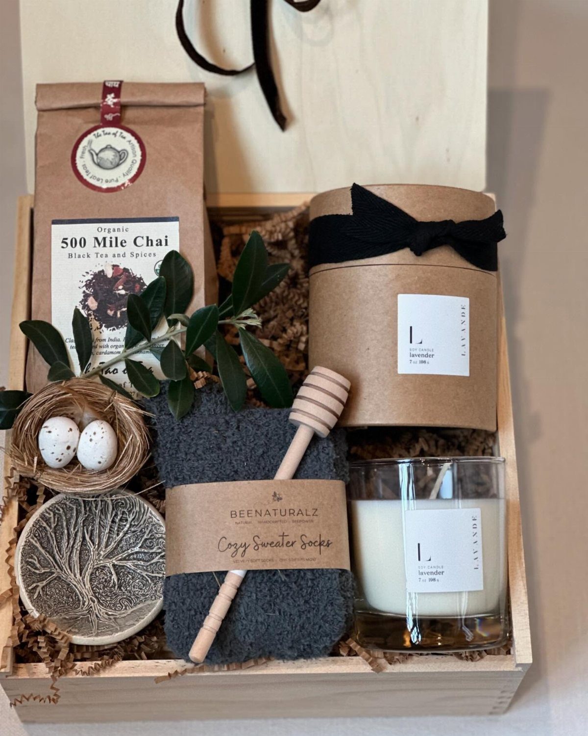 Wooden gift box with chai tea, candle, grey socks, and honey dipper.