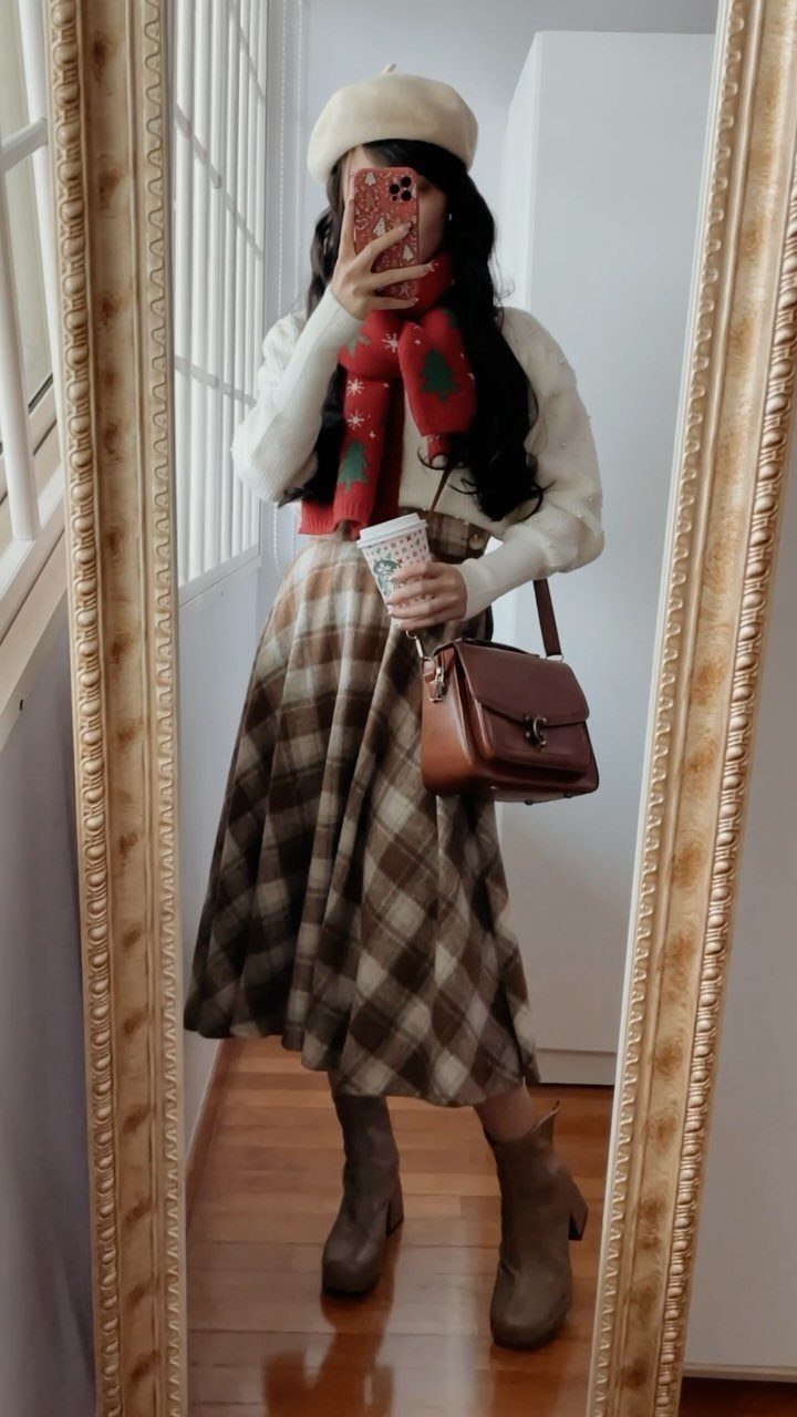 Person in white sweater and red holiday scarf wearing a plaid midi skirt.